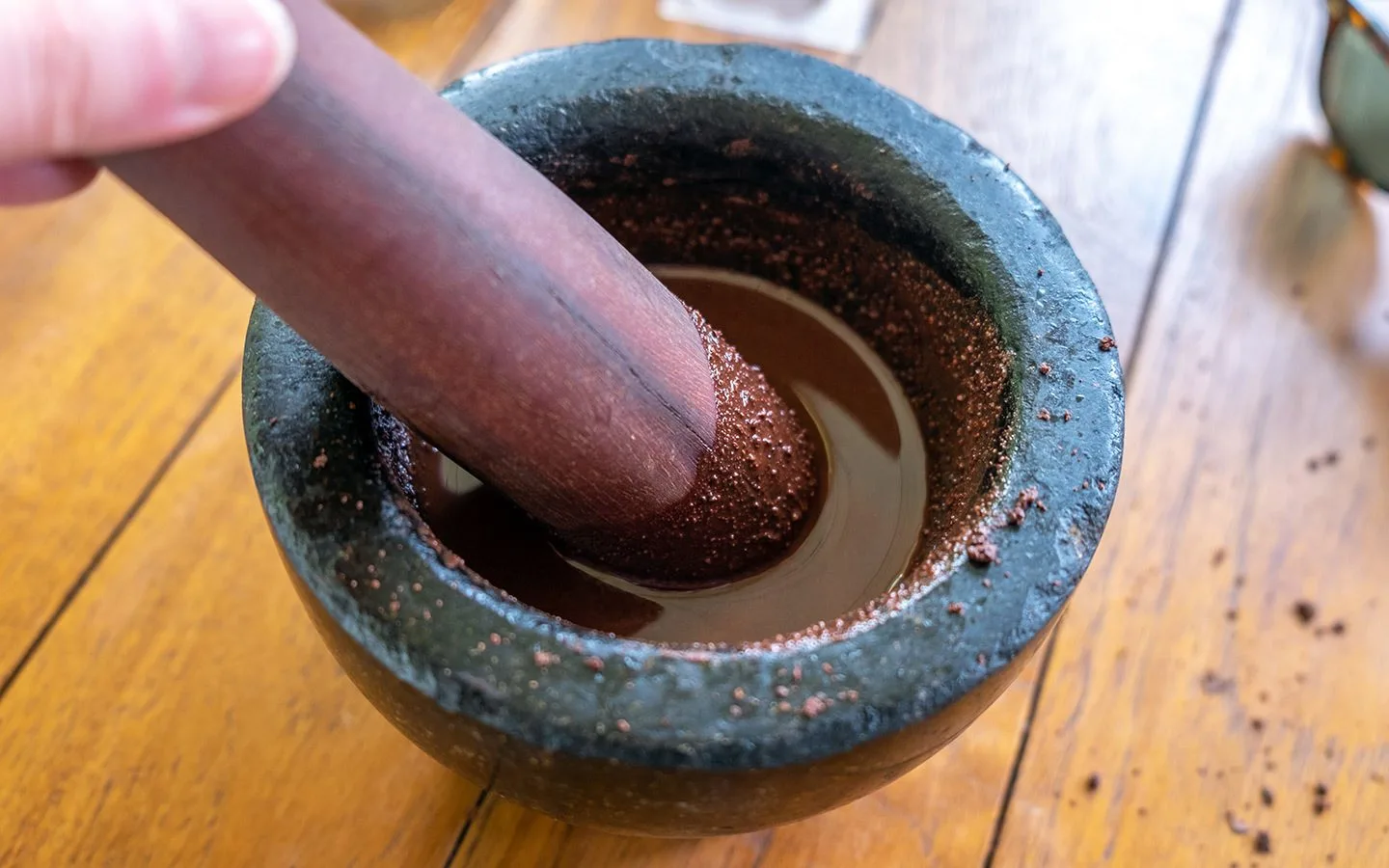 Blending chocolate in a pestle and mortar on a St Lucia chocolate tour with Hotel Chocolat