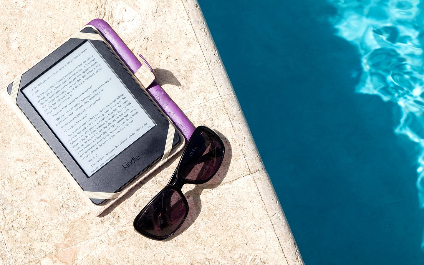 Kindle and sunglasses by the pool